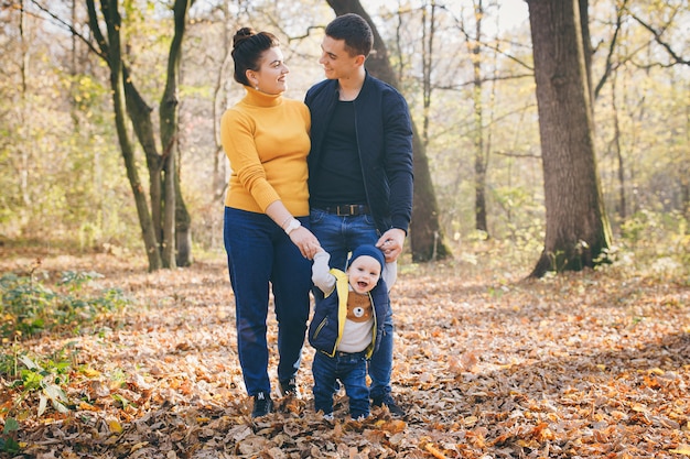 Joven familia feliz mientras caminaba en el parque de otoño. Familia e hijos caminando en el parque de otoño y pasar un buen rato.