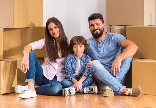 Joven familia feliz mudándose a una nueva casa, abriendo cajas.