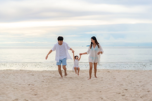 Joven familia feliz en la playa de arena