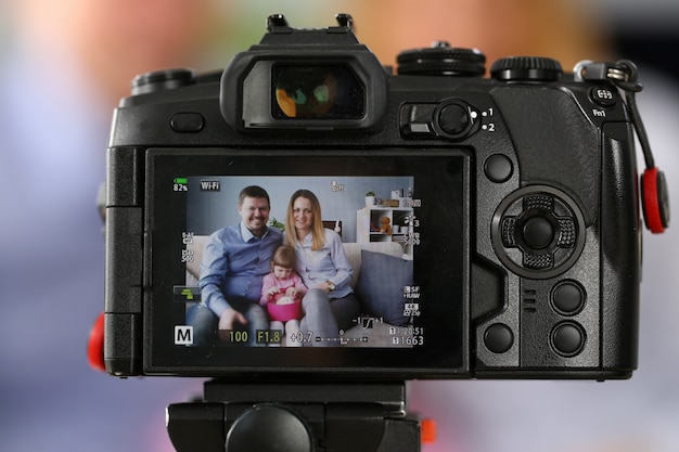 Joven familia feliz sentarse en el sofá haciendo fotos sesión retrato