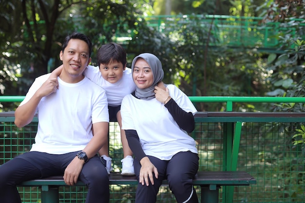 Joven familia feliz de tres divirtiéndose juntos al aire libre. Los padres y el hijo se ven felices y sonríen. Feliz