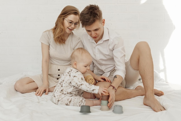 Joven familia hermosa sonriente con bebé infantil querubín jugando con tazones de silicona pastel modernos o