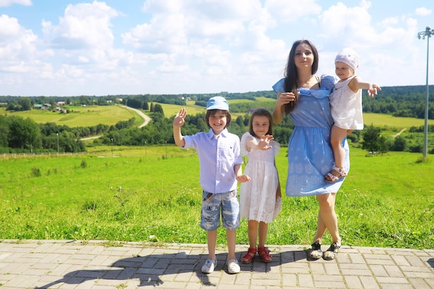 Joven familia numerosa en un paseo matutino de verano Hermosa madre con niños está jugando en el parque