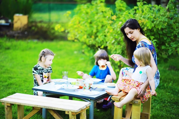 Una joven familia numerosa en un picnic en una mañana de verano Madre con hijos está desayunando en el parque