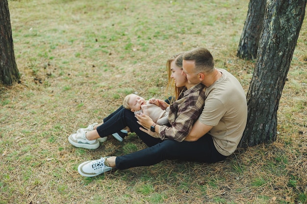 Foto una joven familia está sentada en la naturaleza con un hijo pequeño en sus brazos una familia camina con un bebé en sus brazos
