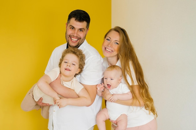 Joven familia sincera donde un padre y una madre felices sostienen a sus adorables hijos en sus brazos Sesión de fotos familiar en el estudio