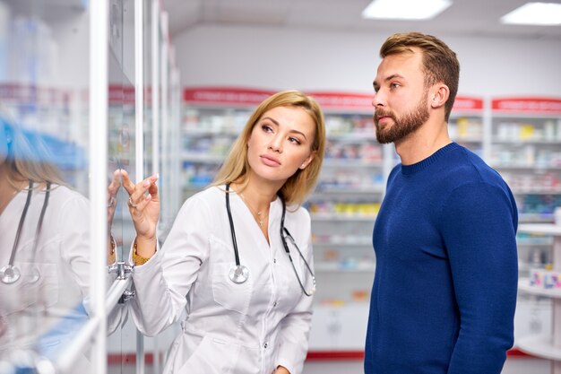 Joven farmacéutico ayudando a cliente masculino enfermo