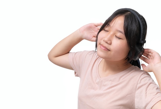 Joven, feliz, atractiva chica asiática con auriculares disfruta escuchando canciones aisladas en blanco