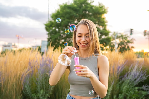 Foto una joven feliz con el cabello suelto sopla burbujas de jabón y ríe