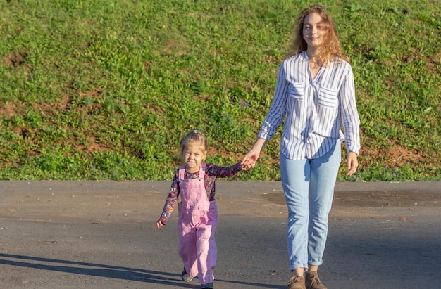 Foto una joven feliz caminando por la carretera tomándose de la mano con una niña