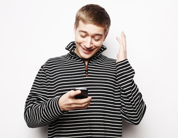 Joven feliz con camisa gesticulando y sonriendo mientras habla por teléfono móvil