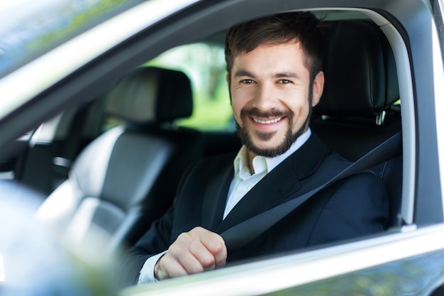 Joven feliz en coche sonriendo - concepto de compra de coche