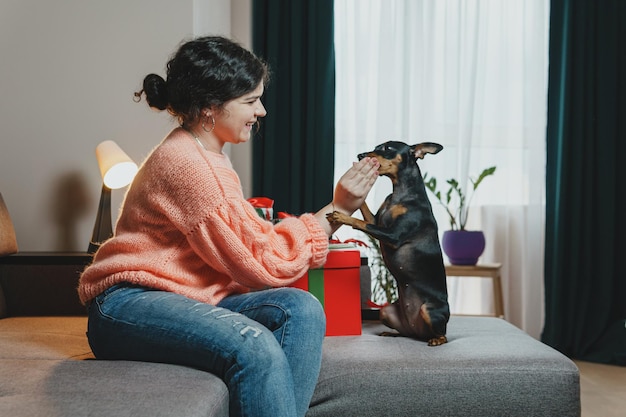 Una joven feliz dando un regalo a su perro de una caja de regalo