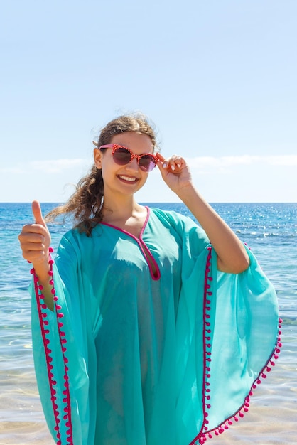 Foto joven feliz dando un signo de mano con los pulgares hacia arriba en la playa