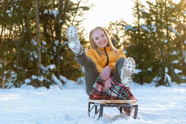Una joven feliz deslizándose en un trineo en el bosque de invierno