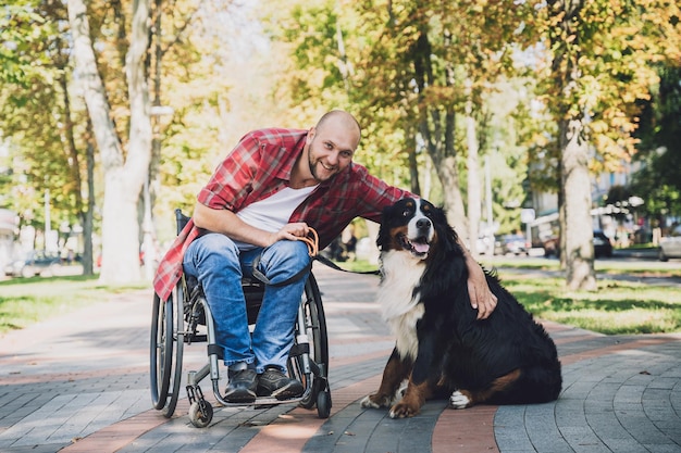 Joven feliz con discapacidad física que usa silla de ruedas con su perro