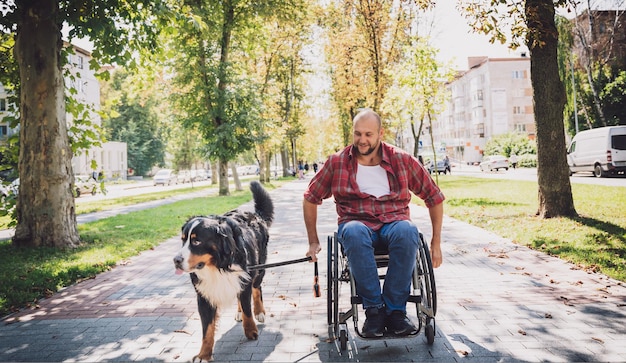 Joven feliz con discapacidad física que usa silla de ruedas con su perro