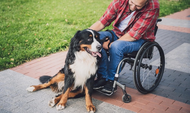 Joven feliz con discapacidad física que usa silla de ruedas con su perro