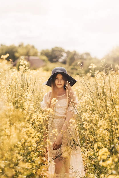 Una joven feliz disfruta de la naturaleza en el campo de la canola floreciente. El corcept de la juventud y la libertad.