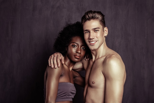 Joven y feliz. Encantado de pareja alegre sonriéndole mientras está de pie juntos