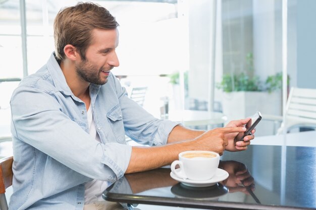 Joven feliz escribiendo en su teléfono