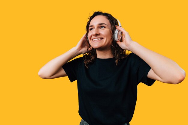Foto una joven feliz está escuchando música con auriculares sobre un fondo amarillo foto de estudio