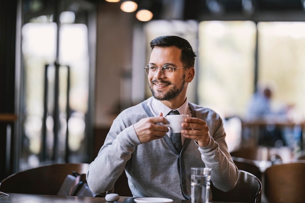 Un joven feliz está bebiendo espresso en la cafetería.