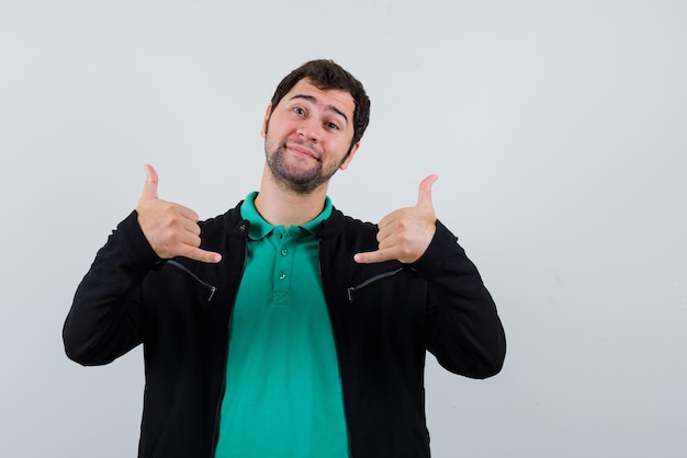 El joven feliz está haciendo gestos con los dedos en el fondo blanco