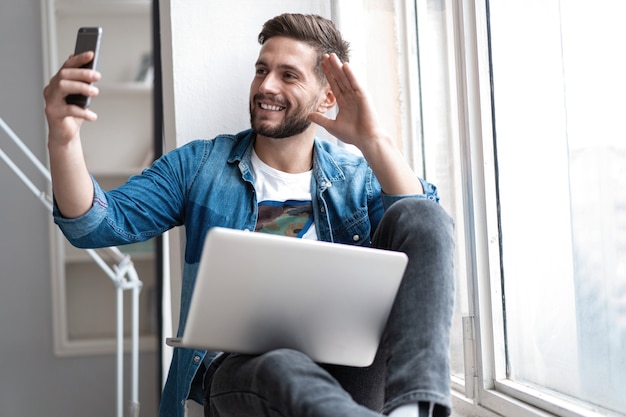 Joven feliz hablando videollamada a través de teléfono inteligente en casa.