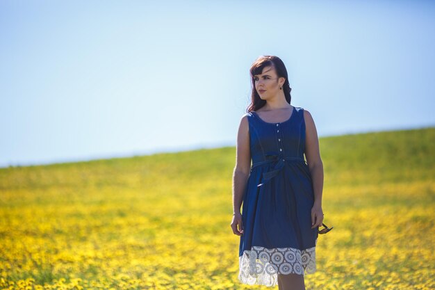 Joven feliz y hermosa chica modelo de gran tamaño con vestido azul en un floreciente campo de dientes de león en verano