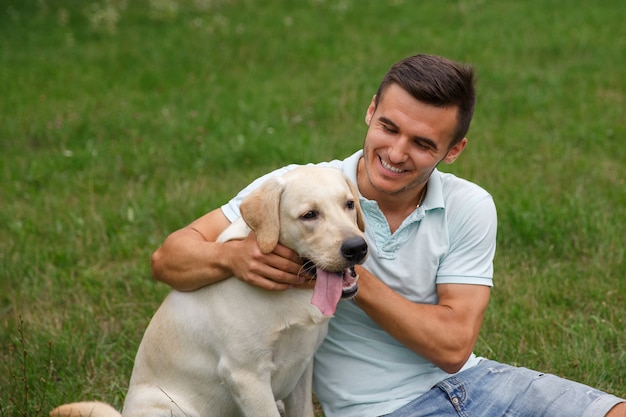 Joven con feliz labrador en el parque