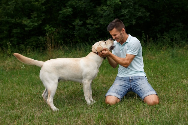 Joven con feliz labrador en el parque