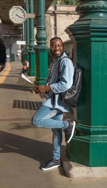 Joven feliz con mapa en la estación de tren terminal