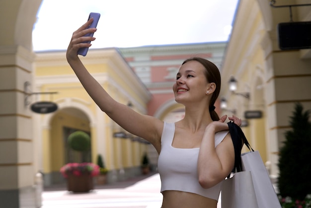 Foto joven feliz mujer hermosa chica elegante está de compras en el centro comercial al aire libre sosteniendo bolsas en la mano