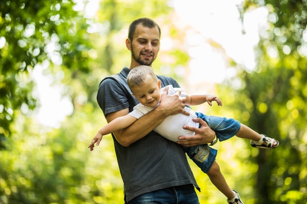 Joven feliz padre e hijo están jugando en el parque