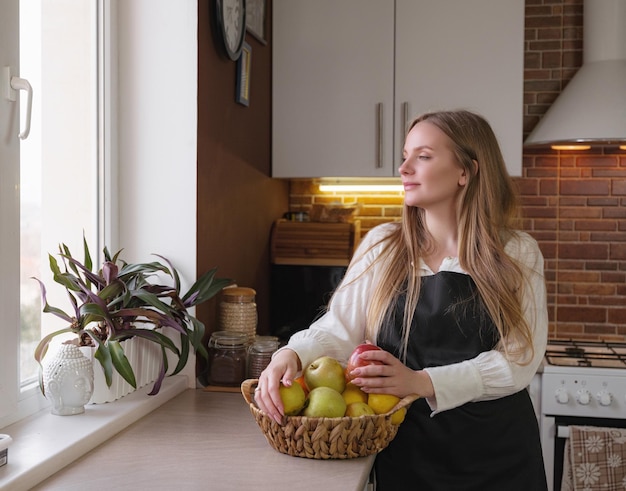 Una joven feliz parada en la cocina mientras cocina