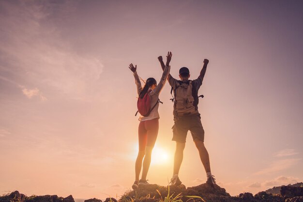 Una joven y feliz pareja sube a la cima de las montañas cerca del océano.