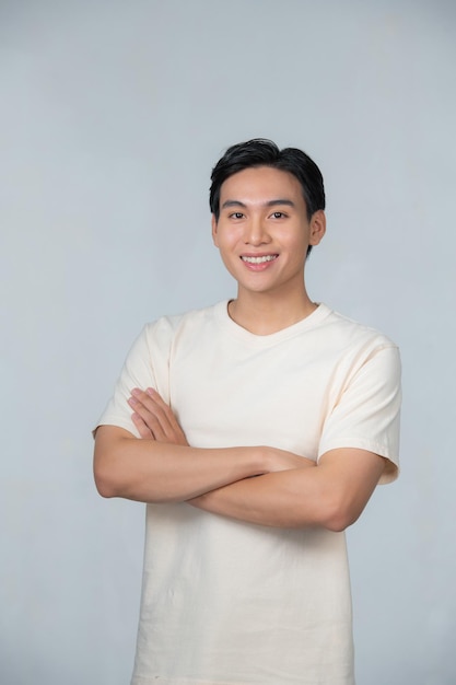 Un joven feliz posando con las manos cruzadas sobre un fondo blanco