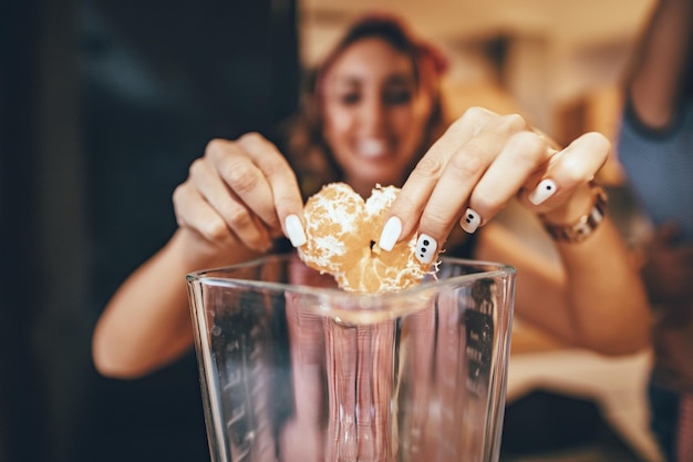 Foto una joven feliz está preparando una comida saludable en la cocina. ella está poniendo rodajas de mandarina en la licuadora.