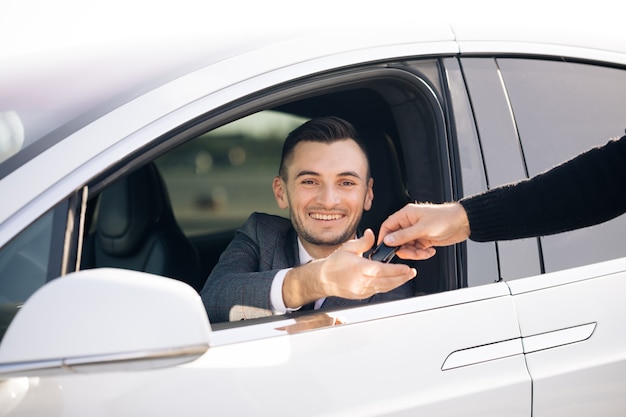 Joven feliz recibiendo las llaves del coche de su nuevo automóvil