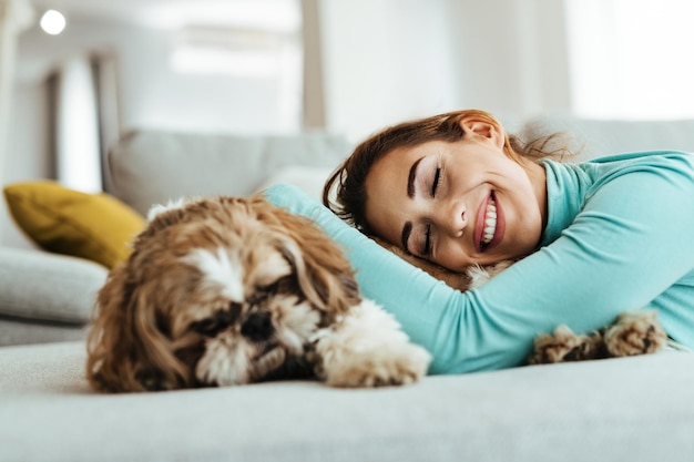 Joven feliz relajándose con su perro en el sofá de casa