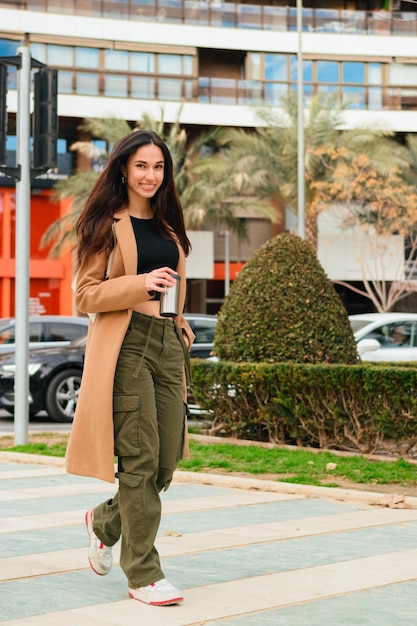 Una joven feliz con ropa informal camina por la calle