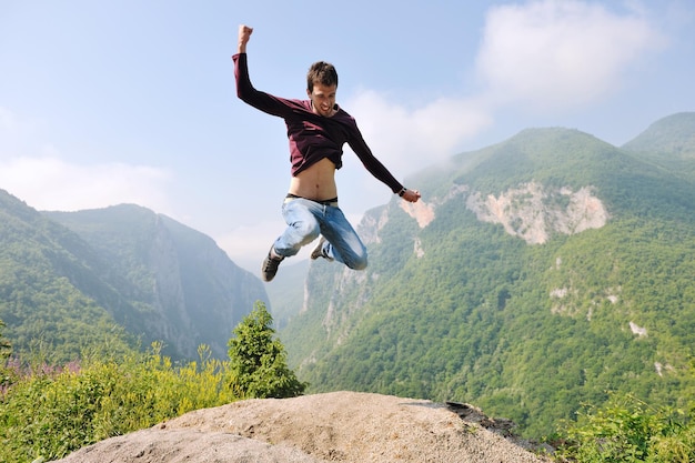 un joven feliz salta a la naturaleza mientras representa un estilo de vida saludable, libertad y concepto activo