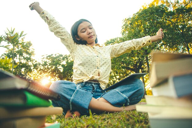 Una joven feliz sentada en una planta contra los árboles