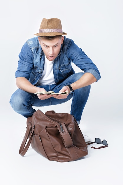 Joven feliz con sombrero encontró dinero en una bolsa de cuero