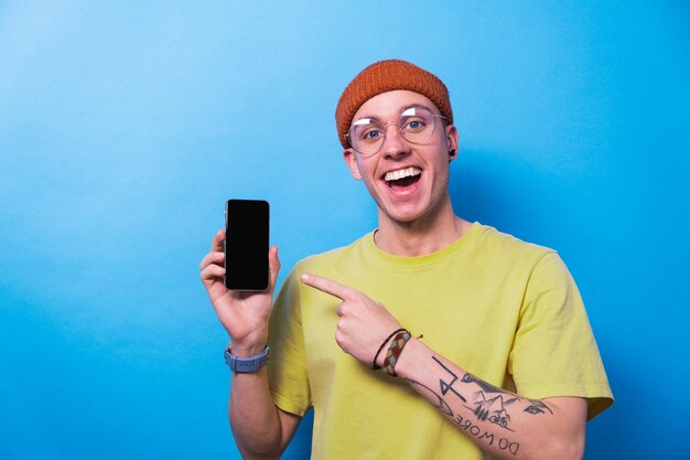 Foto joven feliz sonriendo mostrando un teléfono inteligente con aplicación móvil pantalla limpia para maqueta