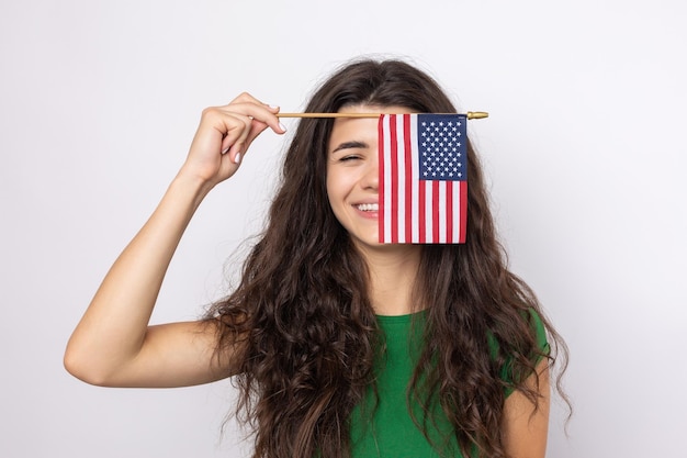 Una joven feliz con una sonrisa en la cara sostiene una bandera estadounidense en sus manos