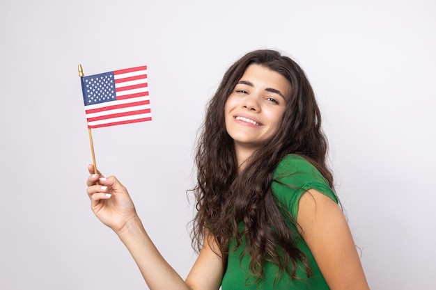 Una joven feliz con una sonrisa en el rostro sostiene una bandera estadounidense en sus manos Símbolo de patriotismo y libertad