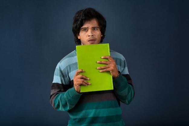 Joven feliz sosteniendo y posando con el libro en el fondo