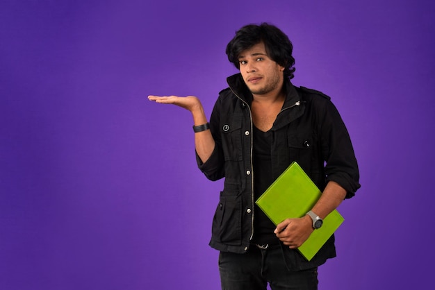 Joven feliz sosteniendo y posando con el libro en el fondo